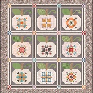 May include: A handmade quilt featuring nine apple-shaped blocks with intricate patchwork designs in various colours. Each apple has a green leaf and stem. The quilt has a grey background with a floral border and a grid pattern.