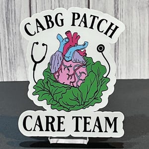 May include: A white sticker with a green cabbage, a pink heart with blue and red veins, and a stethoscope. The text "CABG PATCH CARE TEAM" is printed on the sticker.