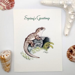 May include: A greeting card with the text "Spring's Greetings" in green lettering. The card features a hand-drawn illustration of a lizard on a rock with green foliage.