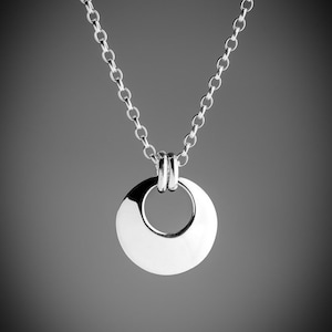 May include: A silver chain necklace with a round pendant featuring a circular cutout. The pendant is smooth and shiny.