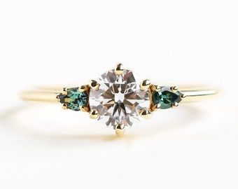 Three stone round diamond engagement ring with side teal pear saphires