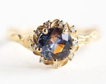 Whimsical round bicolor sapphire ring with leaf diamond halo