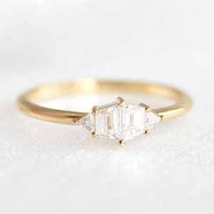 Trapezoid diamond ring. Stones are hold with round prongs. The diamond ring is set in yellow gold. Style of the ring is art deco.