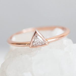 May include: A rose gold ring with a triangular shaped diamond set in a bezel setting.