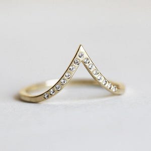 Peut inclure: Une bague en or avec une bande en forme de V sertie de petits diamants.