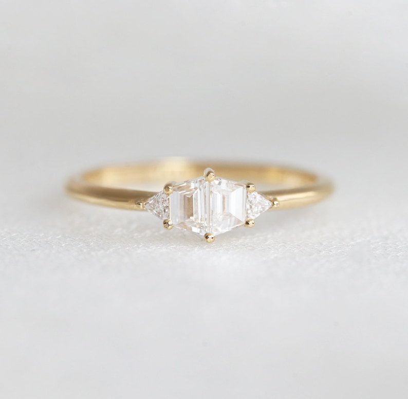 Trapezoid diamond ring. Stones are hold with round prongs. The diamond ring is set in yellow gold. Style of the ring is art deco.