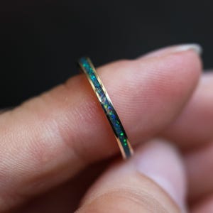 Peut inclure: Une fine bague en or avec une rangée d'opale verte et bleue.