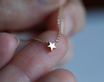 May include: A delicate gold chain necklace with a small, simple star pendant.