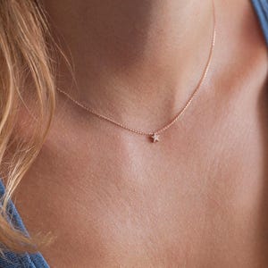 May include: A delicate gold chain necklace with a small, sparkling star pendant.