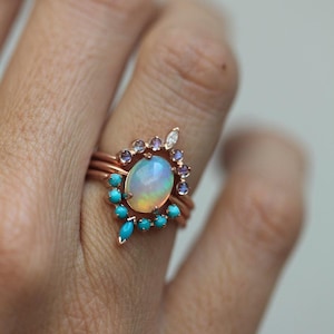 May include: A rose gold ring set with a large oval opal surrounded by a halo of turquoise and amethyst stones.