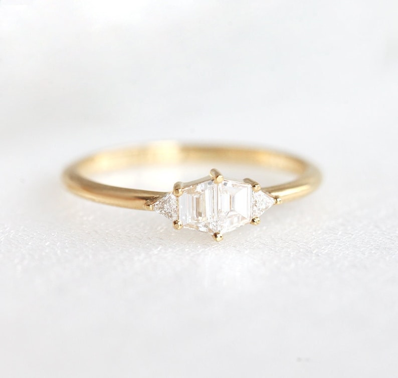 Trapezoid diamond ring. Stones are hold with round prongs. The diamond ring is set in yellow gold. Style of the ring is art deco.