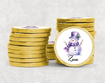 May include: A stack of gold chocolate coins with a personalized design featuring a watercolor snowman with a purple hat and scarf. The coin has the name "Zara" printed on it.