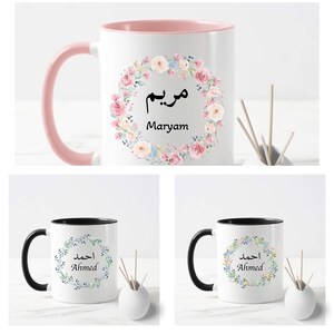 May include: Three white ceramic mugs with black handles. Each mug features a floral wreath design with a name in Arabic script and English. The names are Maryam, Ahmed, and Ahmed.