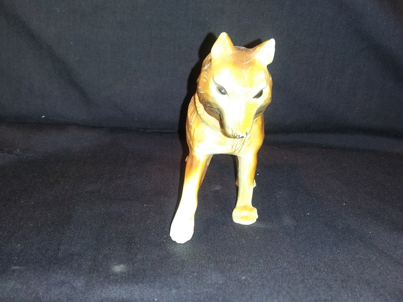 May include: A ceramic figurine of a wolf, standing on all four legs. The wolf is brown and white with black eyes. The figurine is approximately 15 cm tall.