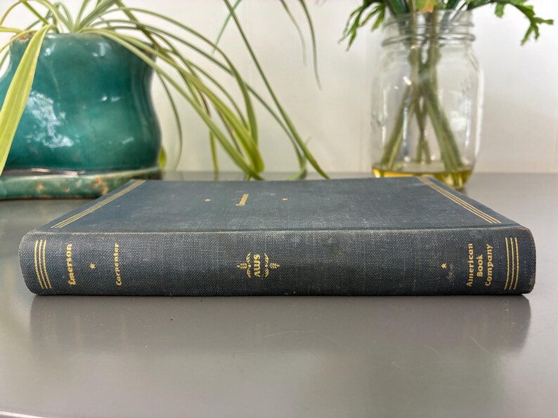May include: A vintage, hardcover book with a dark blue cover and gold lettering. The book's spine features the text "Emerson Carpenter" and the logo "AWS". The book is from the "American Book Company".