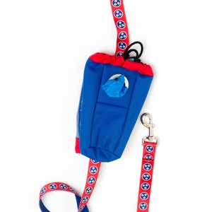 May include: A red and blue dog leash with a matching blue and red poop bag dispenser. The leash has a repeating pattern of paw prints.