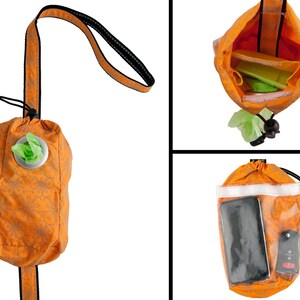 May include: Orange and white patterned bag with a drawstring closure and a clear plastic window. The bag has a strap and is designed to hold dog waste bags, a phone, and other small items.