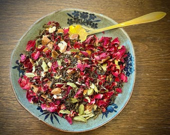 Könnte beinhalten: Eine blaue und weiße Keramikschale gefüllt mit einer Mischung aus losen Blatttee. Der Tee enthält grünen Tee, getrocknete Rosenblätter, Mandeln und Kardamomkapseln.