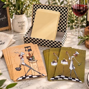 Peut inclure: Un ensemble de cartes de correspondance rectangulaires illustrées d'un chef cuisinier, présentées avec une boîte de rangement à damier noir et blanc remplie de cartes crème. Les cartes montrent un chef avec une toque et un pantalon à carreaux.