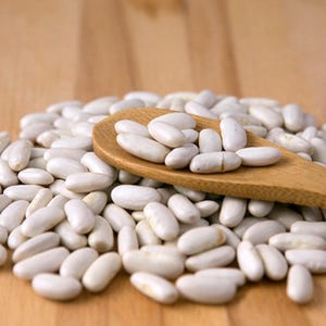 Peut inclure: Une cuillère en bois remplie de haricots blancs repose sur un tas de haricots blancs. Les haricots sont de forme ovale et ont une texture lisse. La cuillère et les haricots sont sur une surface en bois brun clair.