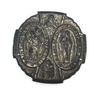 May include: A silver-toned metal religious medal with three oval-shaped images of saints. The medal is decorated with intricate details and has a cross at the top.