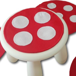 May include: Three red felt mushroom-shaped floor cushions with white polka dots. One cushion is on a white plastic stool.