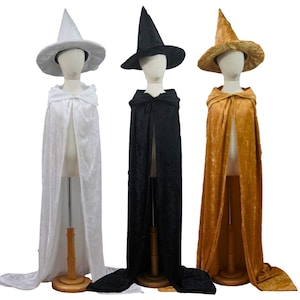 May include: Three witch costumes with pointed hats and long capes. The capes are white, black, and gold.