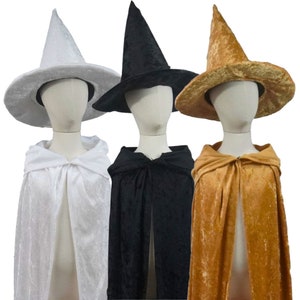 May include: Three witch costumes with hats and capes. The hats are black, white, and gold. The capes are black, white, and gold.