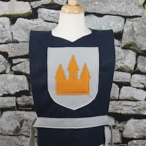 May include: A black felt costume vest with a grey felt castle emblem. The castle is orange felt.