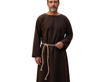 May include: A long-sleeved, floor-length dark brown robe featuring a simple round neckline and a loose, straight-cut silhouette. The garment is cinched at the waist with a thick, light-colored braided rope belt that hangs down the front side.