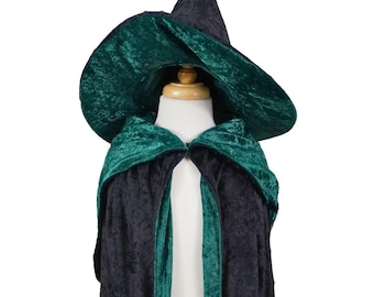May include: A black and green witch costume set. The set includes a pointed hat and a hooded cape. The hat and cape are made of a velvet-like material. The hat is black, and the cape is black with green trim.