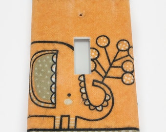 May include: Orange light switch cover with a black and white illustration of an elephant with a flower on its head.