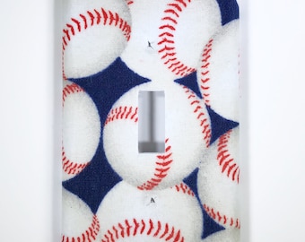 May include: A white light switch cover with a blue background and a pattern of white baseballs with red stitching.