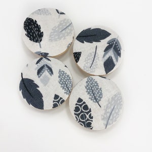 May include: Four round fabric buttons with a white background and a black and gray leaf pattern.