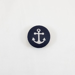 May include: A dark blue fabric button with a white anchor design.
