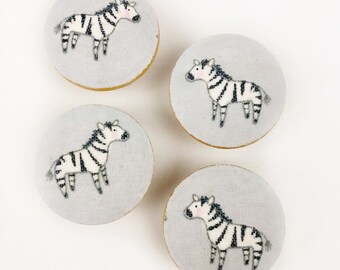 May include: Four round, gray fabric knobs with a white zebra design. The knobs are approximately 2 inches in diameter.