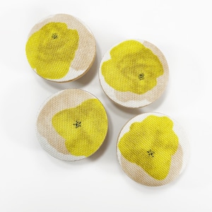 Könnte beinhalten: Vier runde Stoffuntersetzer mit gelbem Blumendesign auf weißem Hintergrund.