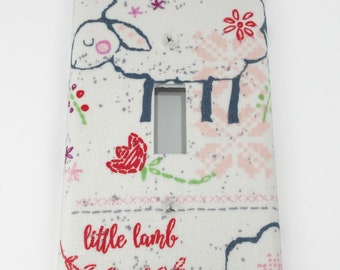 May include: White light switch cover with a pink and gray lamb illustration and the text "little lamb" in red embroidery.