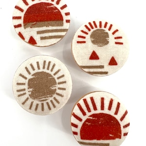 May include: Four round fabric coasters with different sunset designs. Each coaster features a white background with a brown or red sun and geometric shapes.