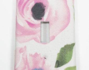 May include: A white light switch cover with a pink floral pattern. The flowers are watercolor-style and have a light pink and dark pink color scheme. There are also green leaves in the pattern.