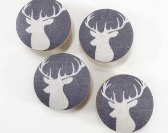 May include: Four gray fabric covered knobs with white deer silhouettes. The deer are facing left and have antlers.