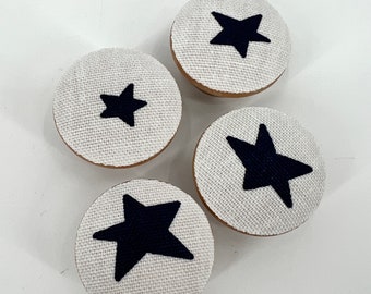 May include: Four white fabric covered knobs with black star designs.