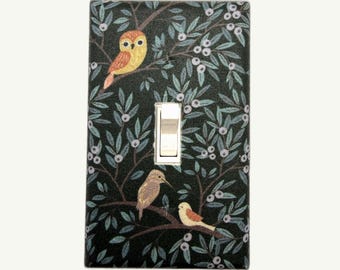 May include: Decorative light switch cover featuring a dark background with a pattern of leaves and berries. The cover has a yellow owl and two birds perched on branches. The switch is a standard toggle style.