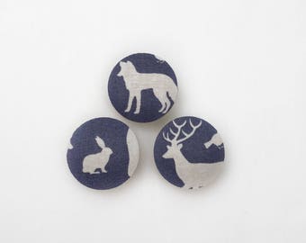 May include: Three round fabric buttons with a navy blue background and white animal silhouettes. The buttons feature a deer, a rabbit, and a wolf.