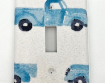 May include: A white light switch cover with a blue and white pattern of vintage pickup trucks.