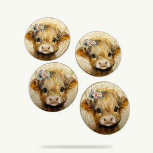 May include: Four round buttons with a light beige fabric background. Each button features a close-up of a brown Highland cow with a floral crown. The cows have dark eyes and pink noses. The buttons are arranged in a square.