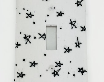 May include: White light switch cover with a black star pattern.