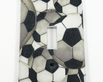 May include: A white light switch cover with a pattern of black and white soccer balls.