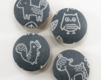 May include: Four round, gray fabric buttons with white animal designs. The designs include a fox, an owl, a squirrel, and a deer.