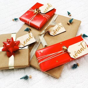 May include: Four wrapped gifts with red and brown paper, tied with twine and ribbon. Each gift has a wooden tag with gold lettering that says "need", "wear", "read", and "want".